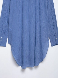 Détail d'une chemise à rayures bleues et blanches avec ourlet arrondi et poignets