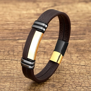 Deep brown braided leather bracelet with golden metal plate on a rustic wood background
