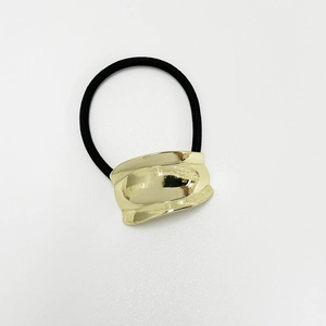 Detail of a black elastic hair tie featuring a polished gold-finish metal curved clasp
