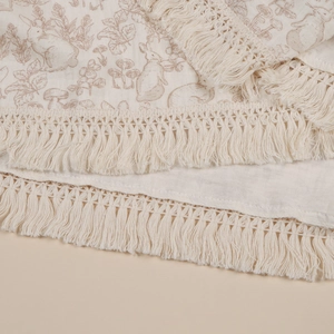 Detailed view of the soft cotton gauze baby blanket with rabbit print and tassels