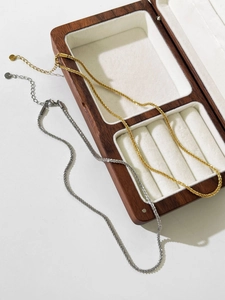 Detail view of gold and silver twisted rope necklaces on a wooden jewelry box