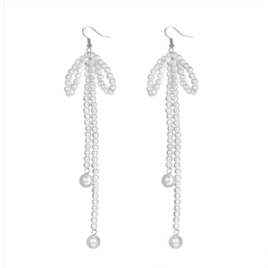 Close-up of white pearl bow earrings with long hanging tassels and silver hooks