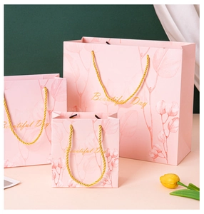 Three sizes of pink gift bags with gold handles and botanical leaf patterns
