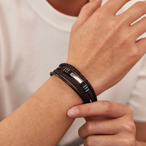 Close-up of a multi-layer black leather braided bracelet with silver metal clasp on wrist