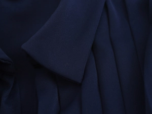 Detailed macro view of the pleated navy satin fabric texture on the elegant long dress