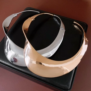 Detailed view of silver and rose gold twisted metal chokers on black leather display