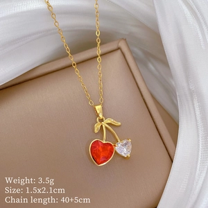 Close-up of gold cherry necklace with red and clear heart crystals on silk background