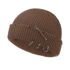 Close-up of vintage brown knit beanie featuring metal safety pin and ring accents