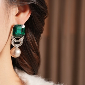 Dettaglio orecchino vintage con pietra verde smeraldo, strass e perla pendente