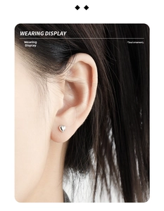 Close-up of minimalist heart stud earring in polished silver finish on model's ear