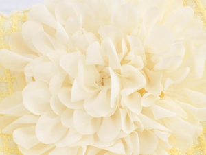 Dettaglio macro di un fiore 3D in tessuto crema applicato su una minigonna in tweed