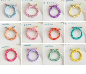 Detail of high-elastic wave-pattern hair ties in 12 vibrant macaron colors on a white dish