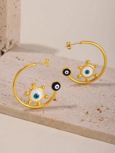 Macro detail of 18K gold plated hoop earrings with blue enamel evil eye on stone