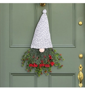 Détail d'une couronne de gnome de Noël avec bonnet en tricot, baies et pommes de pin