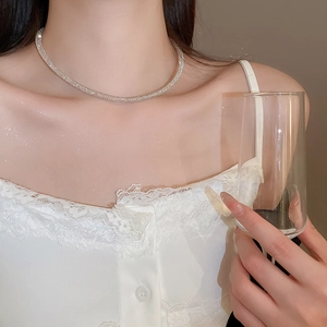 Close-up of sparkling zircon twisted mesh necklace on model neck with elegant shiny finish
