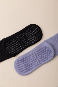 Detail view of non-slip silicone grips on purple and black cotton yoga socks