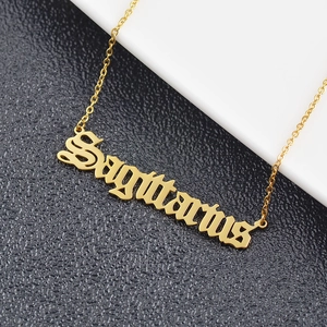 Macro detail of golden Sagittarius pendant in Gothic font on a delicate link chain