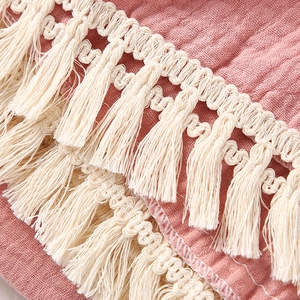 Detail of pink double-layer cotton muslin blanket with delicate beige fringe trim