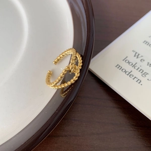Minimalist double-layer twisted rope gold open ring for women on a ceramic plate