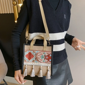 Ethnic embroidered canvas tote bag with bohemian floral patterns and tassels worn by model