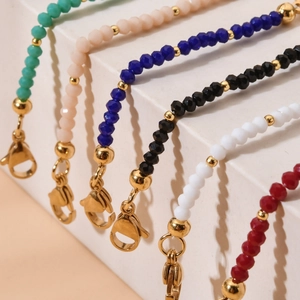 Detailed view of colorful beaded lanyards with gold accents on a beige display stand