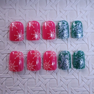 Short Christmas press-on nails with red snowflake patterns and green glitter stripes