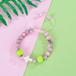 Detailed shot of pink zebra stone bracelet with tennis beads and a white cross charm