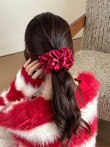 Close-up of a red satin oversized scrunchie on a ponytail with elegant pleats and high gloss