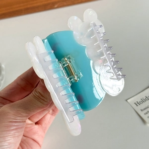 Blue and white marble acetate butterfly hair claw clip held against a neutral background