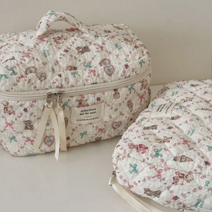 Detail of quilted floral makeup bag featuring bear patterns and ribbon zipper pull