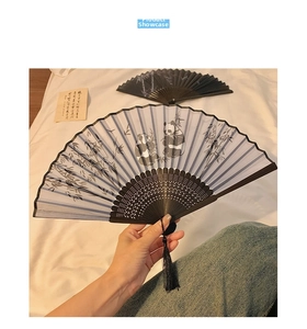Detail of bamboo hand fan featuring giant panda ink painting with black silk tassel