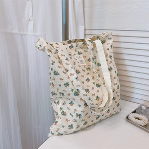 Detailed view of cream floral tote bag with textured cotton fabric and woven labels