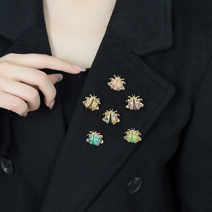 Detail showing six colorful beetle brooches with crystals on a black suit lapel