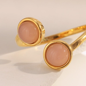 Détail d'une bague plaquée or 18 carats avec deux pierres roses sur fond de pierre beige