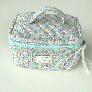 Quilted floral makeup bag in light blue and purple with top handle and ribbon zipper