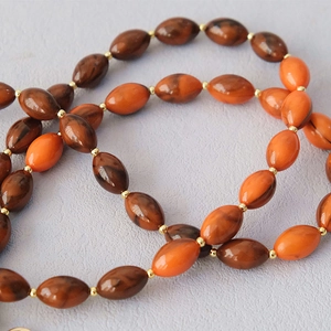 Détails macro de perles en acrylique orange et marron avec intercalaires dorés