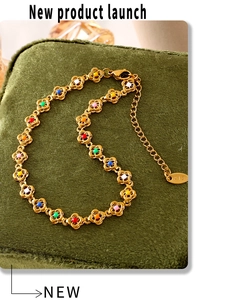 Close-up of 18K gold floral bracelet with colorful enamel petals on green velvet