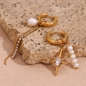 Detailed view of asymmetric gold star earrings with freshwater pearls and tassels