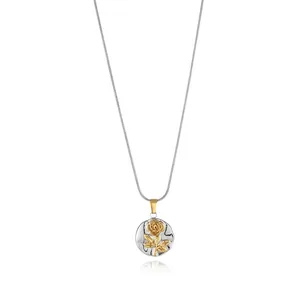 Macro detail of silver brushed circular pendant featuring a golden rose flower design