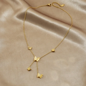 Gold butterfly necklace with textured pendants on elegant champagne silk background