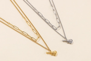 Detailed view of layered gold and silver guitar necklaces with paperclip chains