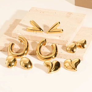Polished 18K gold-plated vintage geometric earrings and heart studs on travertine stone