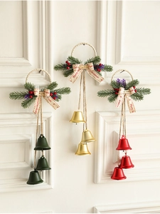 Close-up of Christmas bells set with pine needles and Merry Christmas ribbons on white wall