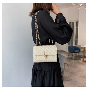 Detail of creamy white quilted crossbody bag with gold chain and metal Y-clasp closure