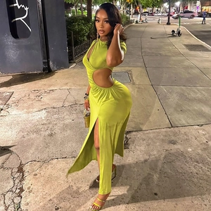 Slim fit neon green cut-out maxi dress with high slit shown on a nighttime street