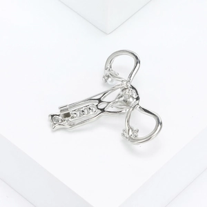 Detailed view of silver uterus brooch with pearls on white geometric background