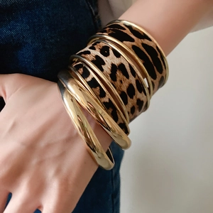 Golden geometric metal bracelets with leopard print pattern worn by a model