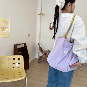 Close-up of lavender canvas tote with plaid straps and side pocket detail