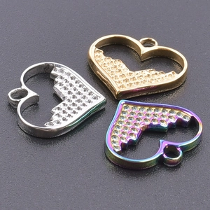 Macro shot of three heart-shaped pendants in gold, silver, and rainbow steel