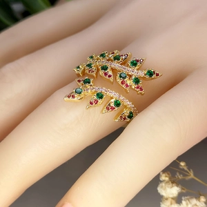 Luxurious gold wheat leaf open ring with green and red zircons shown on a hand